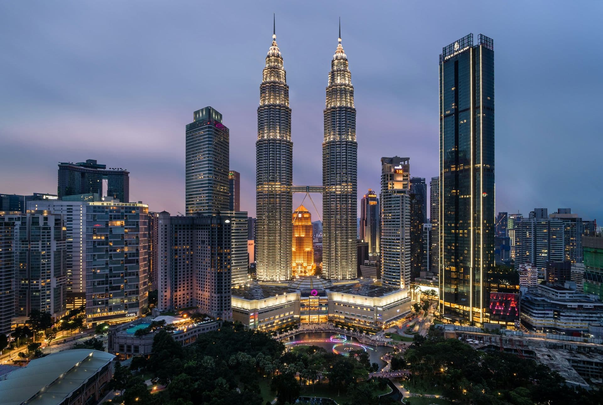 The Petronas Towers lit up at dusk above the Kuala Lumpur skyline