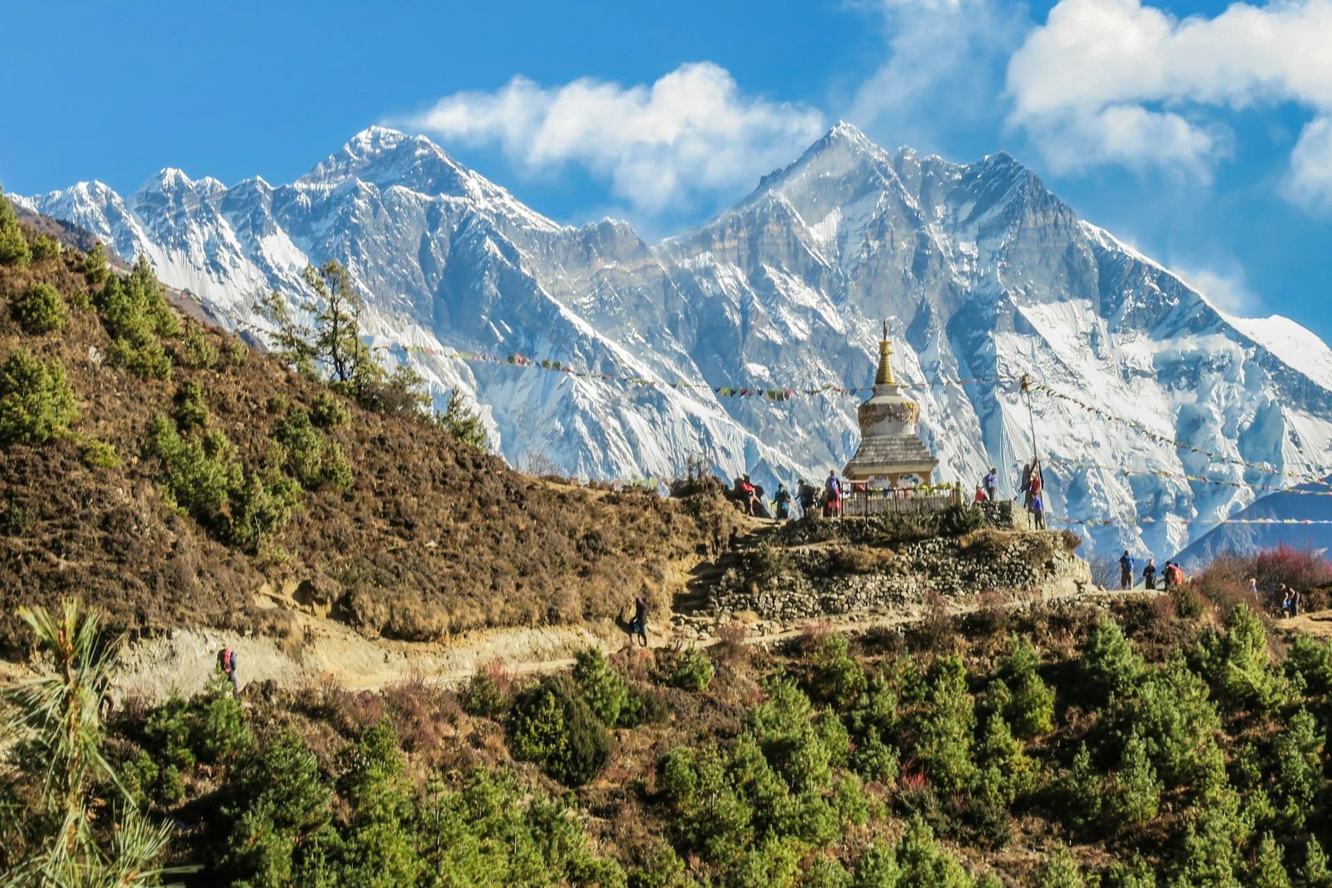 Snow-covered Himalayan peaks above a stupa on a trekking trail