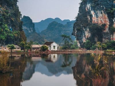 Limestone cliffs above a still river and a small house